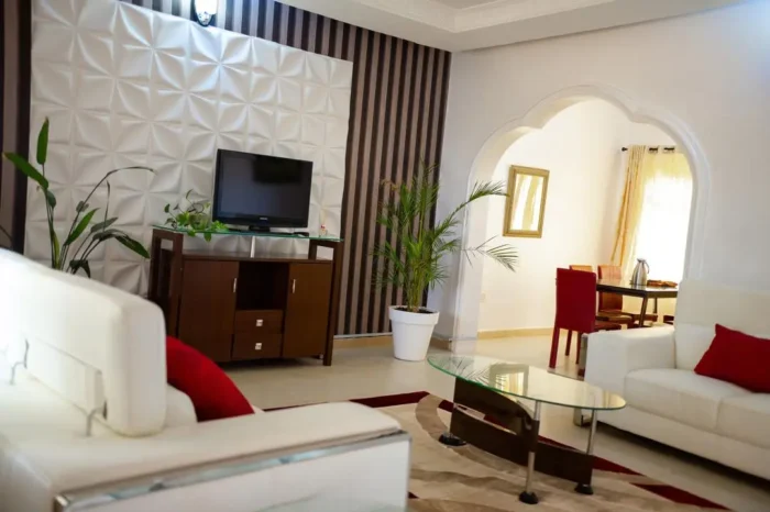 Different view of sitting area of Carter conlon resort in Jos featuring white counches, TV, flowers and center table