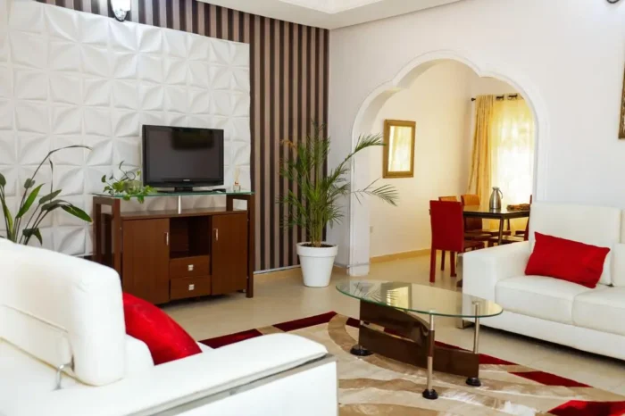 Different view of sitting area of Carter conlon resort in Jos featuring white counches, TV, flowers and center table